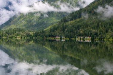 Dağların ve geçen yük treninin bir gölün yüzeyine simetrik olarak yansıyan bir resmi. BC Kanada