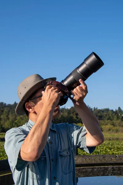 Şapkalı Güneş Gözlüklü Asyalı Bir Adamın Resmi Kamerasını Gökyüzüne Doğrultuyor — Stok fotoğraf