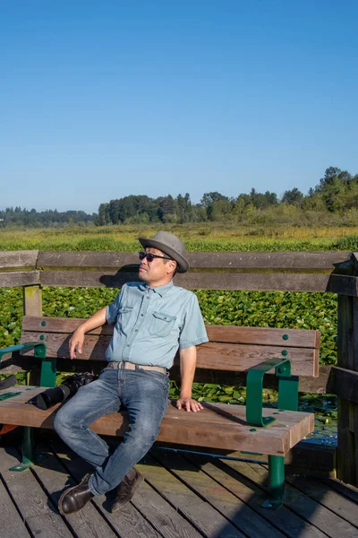 Yanında Kamera Olan Asyalı Bir Adam Parkta Bir Bankta Oturup — Stok fotoğraf