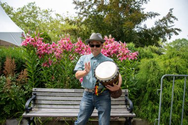 Asyalı bir adam ayakta ve djembe çalıyor. Vancouver BC Kanada