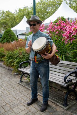 Asyalı bir adam ayakta ve djembe çalıyor. Vancouver BC Kanada