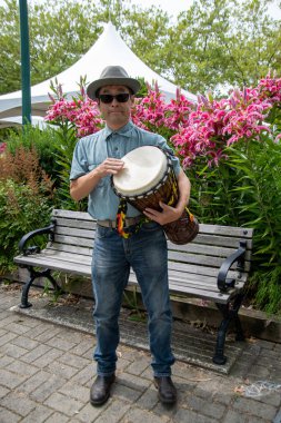 Asyalı bir adam ayakta ve djembe çalıyor. Vancouver BC Kanada