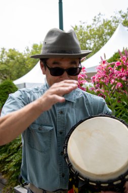 Asyalı bir adam djembe çalarken eğleniyor. Vancouver BC Kanada