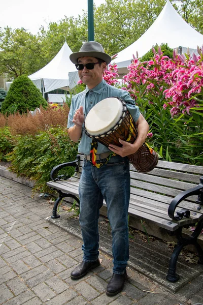 Asyalı bir adam ayakta ve djembe çalıyor. Vancouver BC Kanada