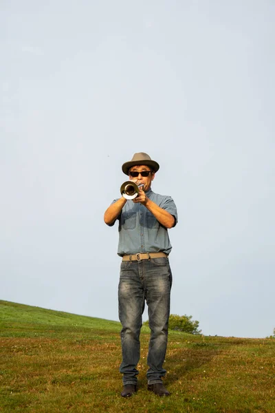 A man playing the trumpet at a park.   Vancouver BC Canada