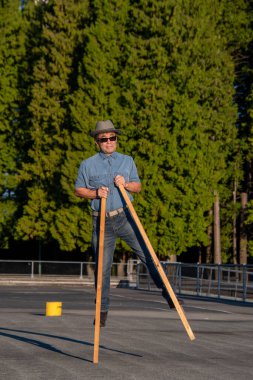 Tahta ayaklıklar üzerinde yürüyen orta yaşlı bir adam. Vancouver BC Kanada