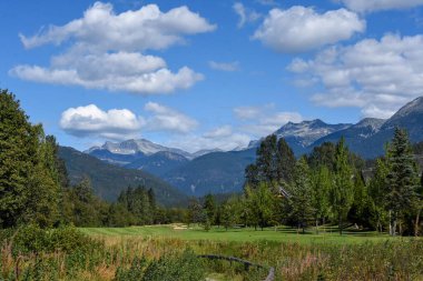 Güzel dağlarla çevrili bir golf sahasının resmi. Whistler BC Kanada