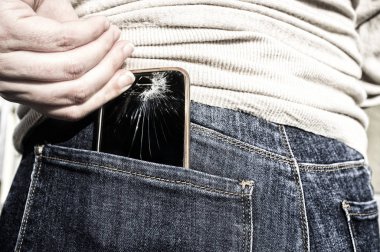 Kadın kırık bir cep telefonu onun cep kot pantolon oturma sonra üzerine yukarı çeker. Carelessnes becerikli alet kavramı hakkında
