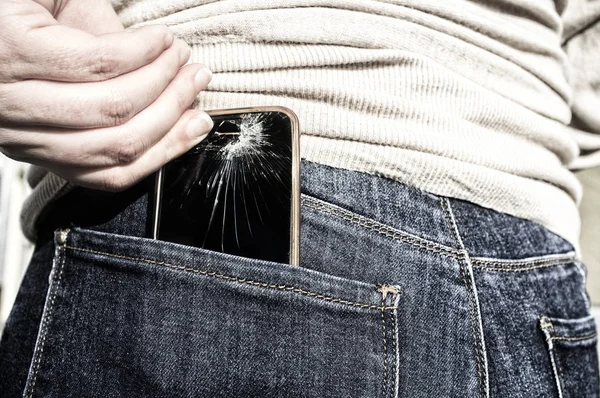 Woman pulls a broken mobile phone up from her pocket jeans pant after sitting over it. Carelessnes about gadgets concept