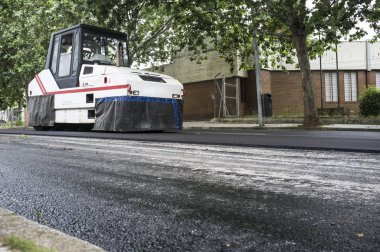 Şehrin asfalt döşeme çalışıyorum. Pnömatik lastik makara makine iş başında