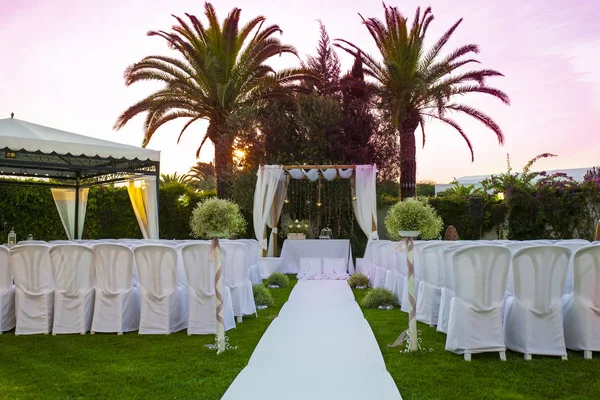 White carpet and chairs for an outdoor wedding. Sun rising light