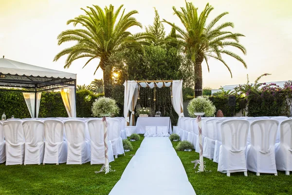 White carpet and chairs for an outdoor wedding. Sunset light