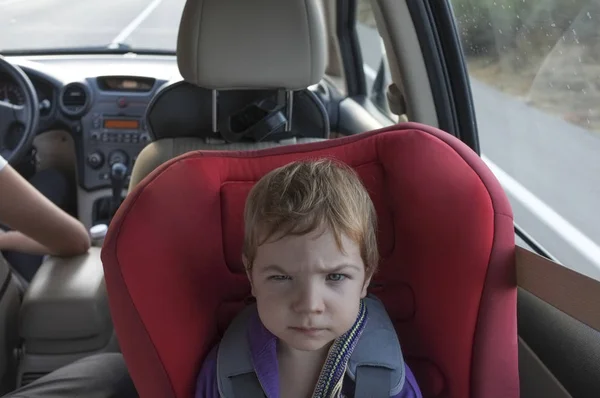Handsome baby boy gets angry on car seat. Surviving a long car journey with children concept
