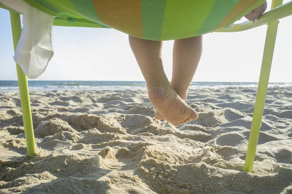 Menino Pés Cheios Areia Ele Está Sentado Cadeira Praia Frente — Fotografia de Stock