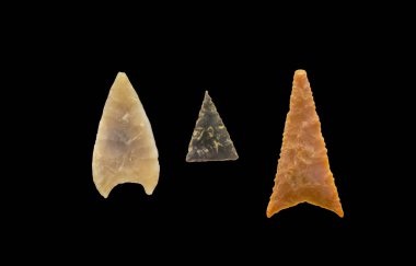 Three late bronze period stone arrow heads. Isolated over black clipart
