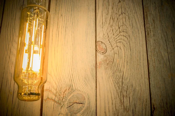 Rope light bulb over weathered wooden background. Low angle view