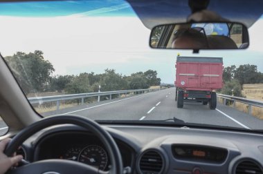 Yavaş yavaş bir traktör römork ile arkasında tarafından yerel kırsal yol sürüş. Sahne sürüş