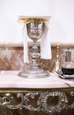 Kilisede mermer masa üzerinde görüntülenen Katolik liturjik nesnelerin. Kadeh, şarap sürahi ve çan
