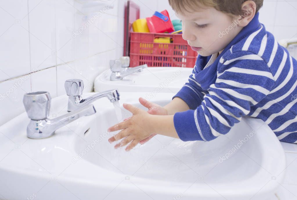 Child boy washing hands at adapted school sink