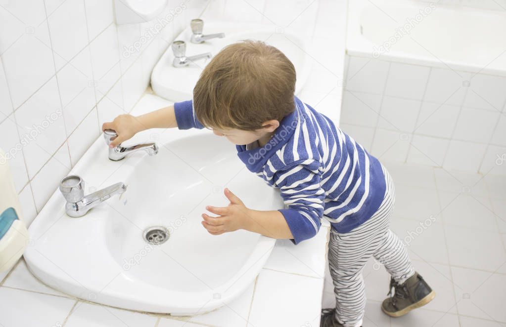 3 years boy washing hands at adapted school sink