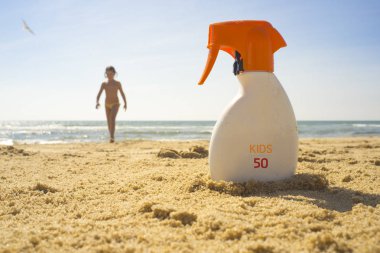 Güneş koruma faktörü veya Spf 50 güneş kremi krem plaj kum üzerinde. Arka plan üzerinde kız çocuk
