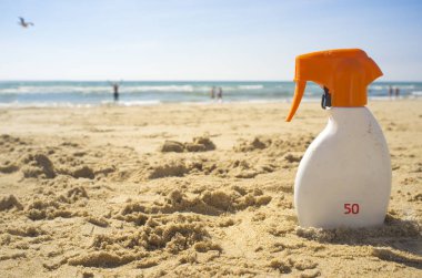 Güneş koruma faktörü veya Spf 50 güneş kremi krem plaj kum üzerinde. İnsanlar arka plan üzerinde