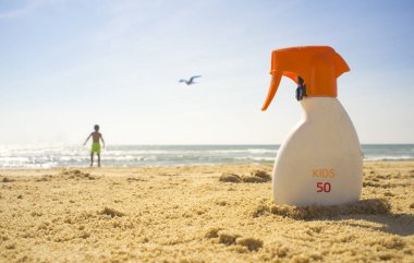 Güneş koruma faktörü veya Spf 50 güneş kremi krem plaj kum üzerinde. Çocuk Çocuk arka plan üzerinde