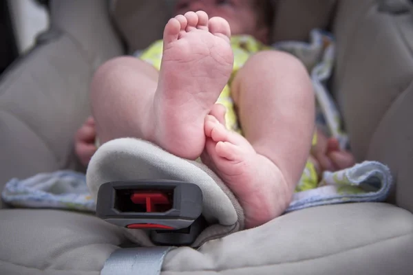 Newborn baby feet over at i-size baby car seat. Low angle shot