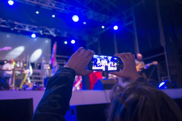 Akıllı telefonu olan bir kadın konserde fotoğraf çekiyor — Stok fotoğraf