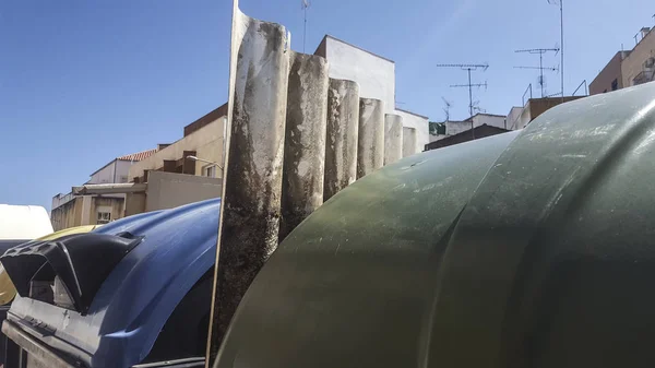 Hojas corrugadas de cemento de fibra tiradas entre botes de basura — Foto de Stock