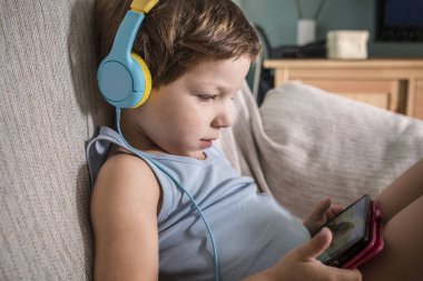 Kulaklıklı 4 yaşındaki çocuk akıllı telefondan video izliyor