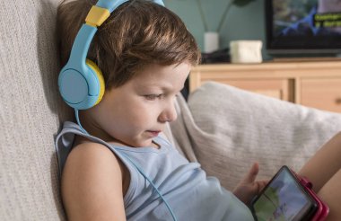 Kulaklıklı 4 yaşındaki çocuk akıllı telefondan video izliyor