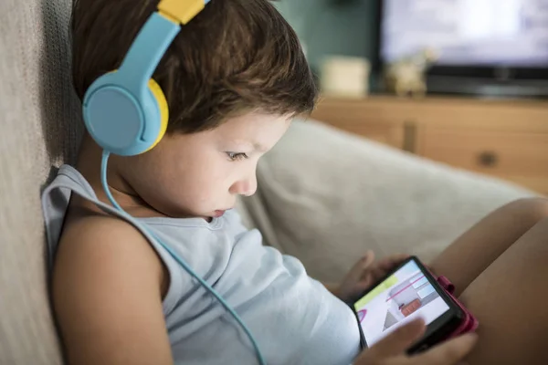 4 años niño en auriculares viendo videos en el teléfono inteligente — Foto de Stock