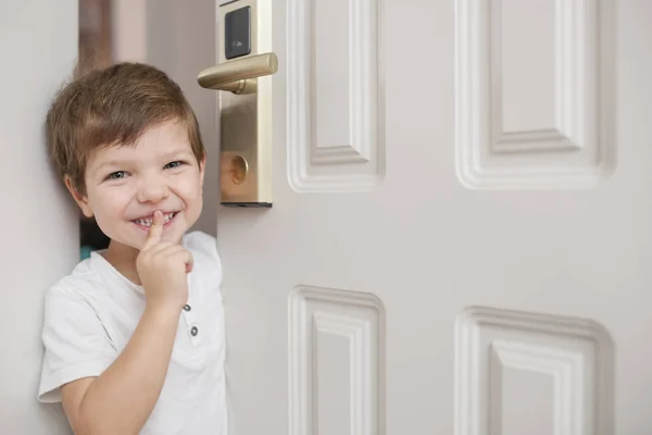 4 años de edad de pie en la puerta y haciendo señal de silencio con su — Foto de Stock