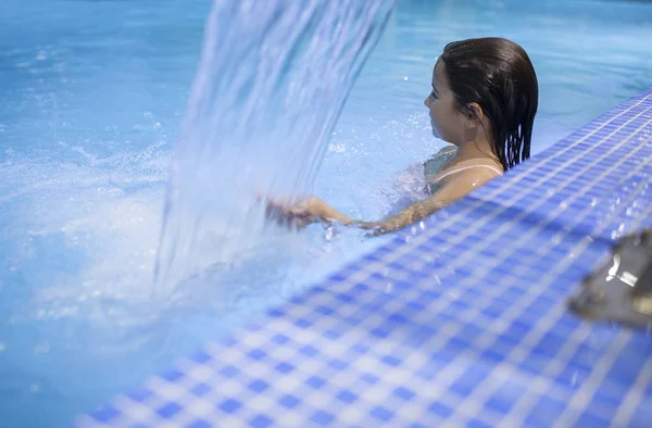 7 years little girl enjoying waterfall jets at indoor pool SPA — Stock Photo, Image