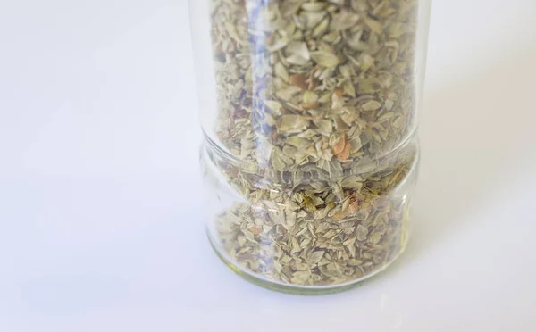Glass bottle of dry oregano leaves — Stock Photo, Image