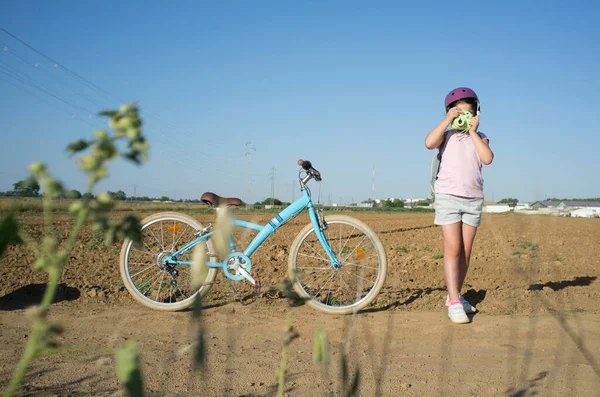 彼女のインスタント写真のカメラで田舎で撮影かわいい女の子 彼女は素敵なレトロな自転車を持っています側に駐車 — ストック写真