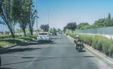 Bisikletin arkasında yavaşça sürüyorlar. Arabanın içerisinden bak.
