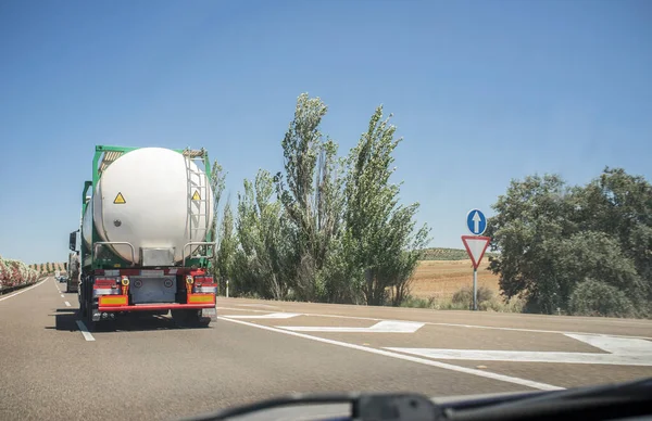 Driving behind slow tanker truck shipping hazardous materials. View from the inside of the car