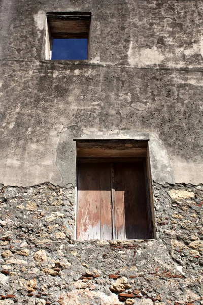 从下面的角度看 在旧石墙上的窗户紧闭的木百叶窗和打开的窗口后 蓝色的天空 — 图库照片