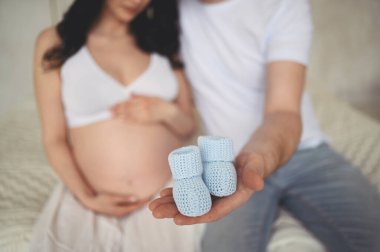 Hamilelik ve insan konsepti. Mutlu bir adam, güzel hamile karısına evde sarılıyor. Doğmamış bebek bekleyen müstakbel ebeveynler. Aşk, ilişki, doğum, mutlu aile kavramı - genç, sevimli evli çift