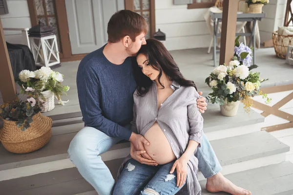 怀孕和人们的观念 快乐的男人在家里拥抱他美丽的怀孕妻子 未来的父母在等待未出生的婴儿 幸福的家庭观念 年轻漂亮的夫妻 — 图库照片