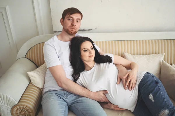 怀孕和人们的观念 快乐的男人在家里拥抱他美丽的怀孕妻子 未来的父母在等待未出生的婴儿 幸福的家庭观念 年轻漂亮的夫妻 — 图库照片