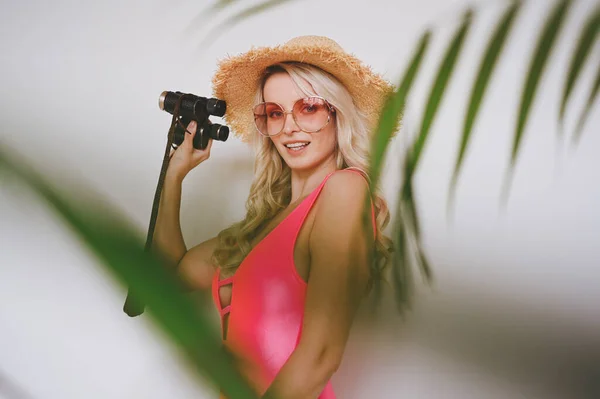 ピンクの水着で若いセクシーな笑顔幸せなブロンド わらの帽子 サングラス 製品を提示する興奮 ヤシの緑の葉を持つ白い背景の女性 夏の販売の概念コピースペースモックアップ — ストック写真