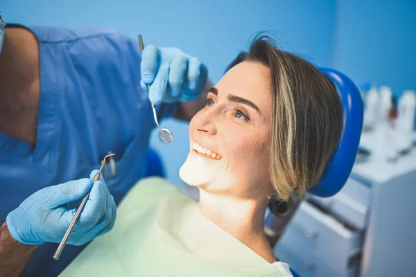 牙科医生在牙科诊所使用牙科设备检查病人的牙齿 口腔医学和保健概念 年轻英俊的男医生 戴着一次性医疗面罩 微笑着快乐的女人 — 图库照片