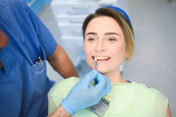 牙科医生用牙医的颜色检查病人的牙齿美白程度 牙科诊所的牙科设备 口腔医学的概念 医生的手戴着医用手套笑着快乐的女人 — 图库照片
