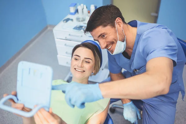 Dentysta Pokazuje Pacjentowi Wyniki Leczenia Lustrem Badając Zęby Sprzętem Stomatologicznym — Zdjęcie stockowe