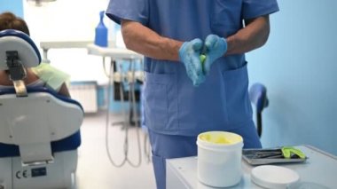 Tıbbi mavi üniformalı doktor dişçi, dişçi muayenehanesinde diş malzemesi kullanarak alçı ya da silikon bir diş kalıbı yapar. Stomatoloji ve sağlık hizmetleri kavramı. 