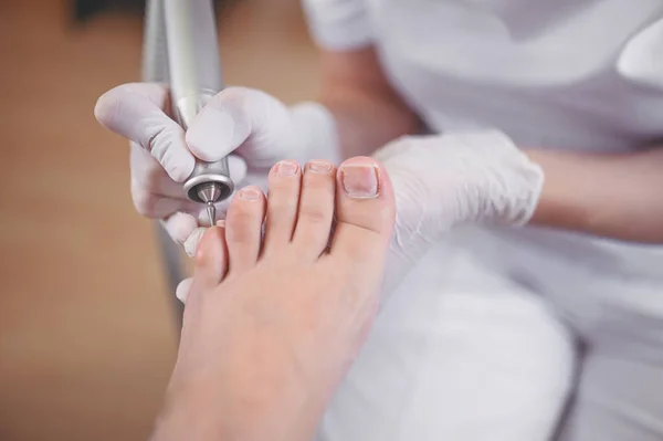 Tırnak törpüsü matkabıyla donanım tıbbi pedikür. Pediyatrist ayak hastalıkları uzmanıyla pedikür tedavisi gören hasta. Özel bir cihazla kaplıcada ayak soyma tedavisi. Podoloji Kliniği.