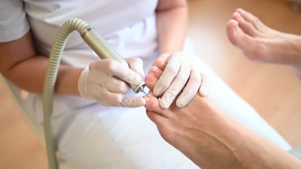 Sprzęt medyczny pedicure z aparaturą do wiercenia paznokci. Pacjent na pedicure z pediatrą, kręgarzem. Leczenie peelingu stóp w spa ze specjalnym urządzeniem. Klinika Podiatrii Podologia — Wideo stockowe